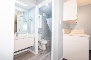 a white bathroom with a toilet and a sink at Ocean Crest Motel in Qualicum Beach