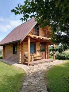Cabaña de madera con porche y banco en Brīvdienu mājiņas Zemzari en Jūrkalne