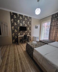 a hotel room with two beds and a desk and a television at Hotel Elio in Batumi