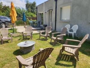 eine Gruppe von Gartenstühlen, einem Tisch und einem Sonnenschirm in der Unterkunft JOLIE MAISON CONTEMPORAINE St Emilion in Néac