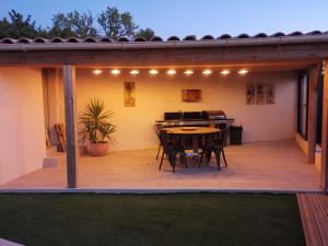 un patio con tavolo, sedie e luci di Maison L'Inattendu avec spa & piscine privatifs a Moussan