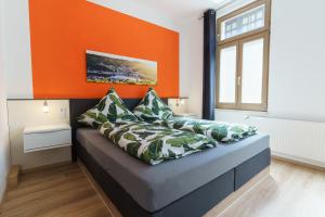 sypialnia z pomarańczową ścianą i łóżkiem z poduszkami w obiekcie Ferienwohnungen Pham w mieście Cochem