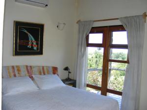 a bedroom with a bed and a large window at Hale Lau in José Ignacio