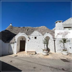 um edifício de tijolos brancos com dois vasos de plantas em frente em Trullo Fanizza em Alberobello