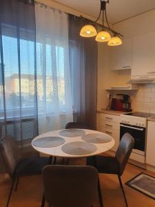 a kitchen with a table and chairs in a kitchen at Moderni, viihtyisä pikkukaksio saunalla in Pori