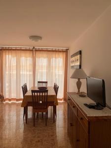 uma sala de jantar com uma mesa com cadeiras e uma televisão em Apartamento vacacional Jávea em Xàbia