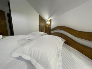 a bedroom with a white bed with a wooden headboard at Casa Bicăjeanului - Lacu Roșu in Lacu Rosu