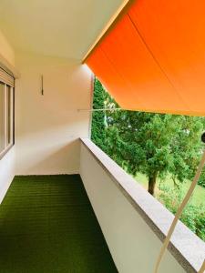 balcón con suelo verde y sombrilla de color naranja en MYM NOW Apartment in Bern, en Berna