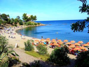 a beach with many umbrellas and people in the water at Nascar Hotel in Santa Maria Navarrese