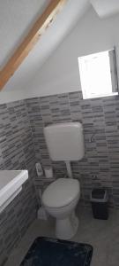 baño con aseo y lavabo y ventana en Ravne weekend house, en Visoko