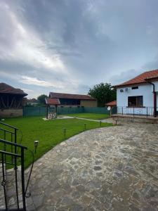 a courtyard with a white building and a grass field at КРУШУНСКИ КЪТ ТЕЯ in Krushuna