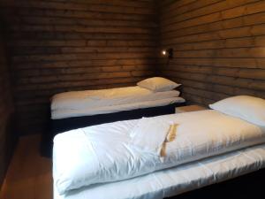 two white beds in a room with wooden walls at Fiskekrogen Rorbuer in Henningsvær