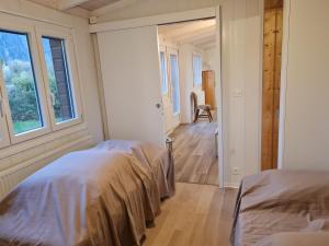 a bedroom with two beds and a hallway with a window at Rhône Cottage 4 in Noville