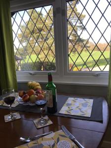 a table with a bottle of wine and a bowl of fruit at Round-y-Corner in Macclesfield