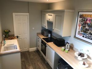 una pequeña cocina con armarios blancos y fregadero en Round-y-Corner, en Macclesfield