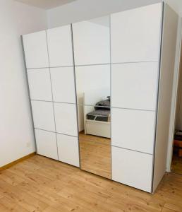 a white closet with a mirror in a room at MYM NOW Apartment in Bern in Bern