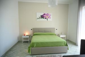 a bedroom with a green bed and two tables at Flowers' House in Castellammare di Stabia