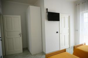 a bedroom with white doors and a television on a wall at Flowers' House in Castellammare di Stabia