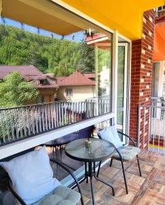 a patio with a table and chairs on a balcony at SARA Apart BelleView in Sinaia