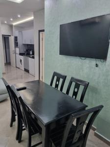 mesa de comedor con sillas y TV en la pared en Comfors Appartements 2, en Fnidek
