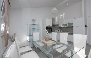 a glass table in a white kitchen with white chairs at Lovely Home In Vinjani Gornji With Wifi in Nenadići