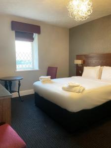Habitación de hotel con cama grande y lámpara de araña. en The Grand Hotel en Port Talbot