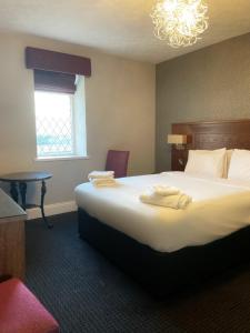 a hotel room with a large bed and a chandelier at The Grand Hotel in Port Talbot