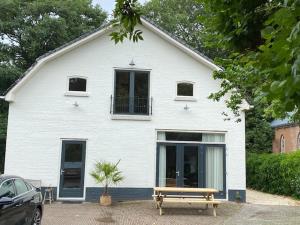 a white house with a bench in front of it at Koetshuys van Villadelfia in Tynaarlo