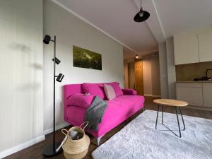 a pink couch in a living room with a table at Apartament Kurort Kozubnik - Taras nad Potokiem in Porąbka