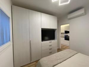 ein Schlafzimmer mit weißen Schränken und einem Flachbild-TV in der Unterkunft Luxury Home & Pool in Lequile