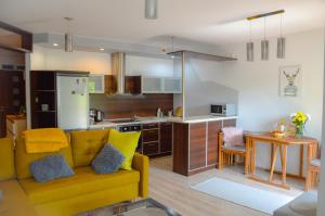 kuchnia i salon z żółtą kanapą w pokoju w obiekcie Apartament Grunwaldzka przy Łynie w Olsztynie