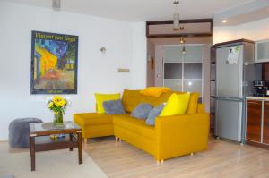 salon z żółtą kanapą i stołem w obiekcie Apartament Grunwaldzka przy Łynie w Olsztynie