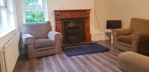 a living room with two chairs and a fireplace at Craigalappan Cottages Holiday Home in Bushmills