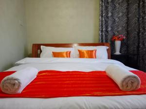 a bed with a red and white blanket on it at The kioka gardens with Wifi and parking in Nanyuki