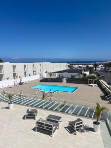 une piscine avec des chaises longues et un complexe hôtelier dans l'établissement Castillo de Luz, à Costa Teguise