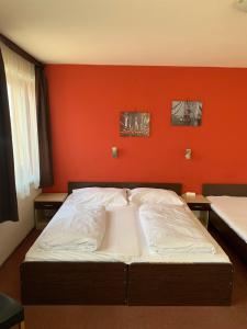 Bett in einem Zimmer mit orangefarbener Wand in der Unterkunft City Hotel Agoston in Pécs