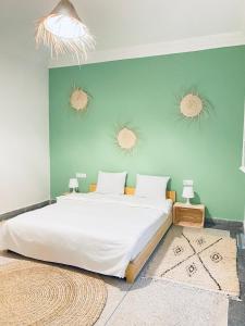 - une chambre avec un grand lit et un mur vert dans l'établissement WELKAM Home & Coworking, à Essaouira