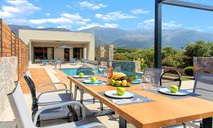 a wooden table and chairs on a patio with a pool at Sissi Lux Villas in Sisi