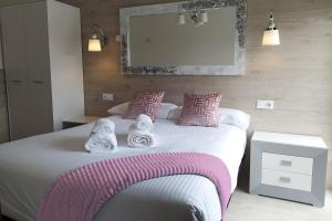 um quarto com uma cama grande com almofadas cor-de-rosa e brancas em Camino del Pinar em Quintanar de la Sierra