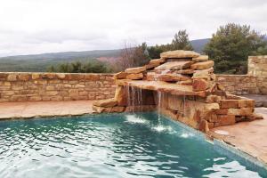 uma piscina com cascata e uma parede de pedra em Camino del Pinar em Quintanar de la Sierra