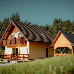 une maison avec un toit noir et une terrasse couverte dans l'établissement Kuća za odmor - Mavis, à Mrkopalj