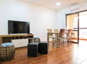 a living room with a tv and a table and chairs at Apto a 200 m da Praia das Pitangueiras-Guaruja SP in Guarujá