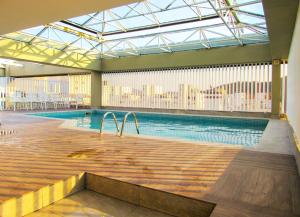 a large swimming pool in a building with a large window at Apto a 200 m da Praia das Pitangueiras-Guaruja SP in Guarujá
