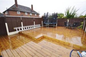 a patio with a wooden deck with water on it at Fabulous 3 bedroom house , sleeps up to 5-7 guest. in South Ockendon