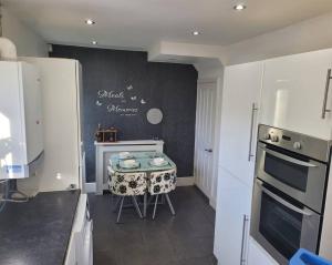 a kitchen with a table and a stove in it at Fabulous 3 bedroom house , sleeps up to 5-7 guest. in South Ockendon
