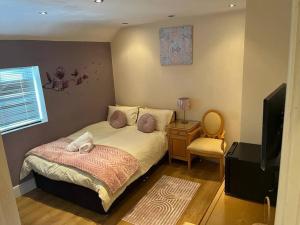 een slaapkamer met een bed met kussens en een televisie bij Fabulous 3 bedroom house , sleeps up to 5-7 guest. in South Ockendon
