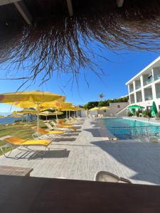 a row of yellow chairs and umbrellas next to a swimming pool at Life Point Hotel in Çeşme
