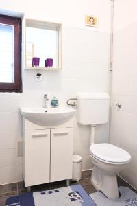 biała łazienka z toaletą i umywalką w obiekcie Zebra w Hvarze