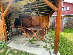 a picnic table under a wooden structure with an oven at Forest Guest House 2 in Sîntimbru-Băi