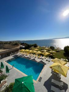 a swimming pool with umbrellas and chairs and the ocean at Life Point Hotel in Çeşme